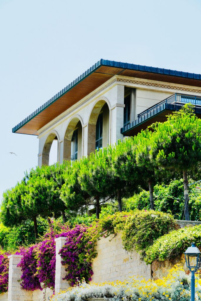 Stunning Mediterranean villa framed by vibrant greenery and florals under a clear sky.